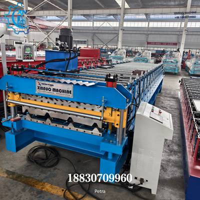 A imagem mostra a &aacute;rea de corte de sa&iacute;da e o sistema de controle da perfiladeira dupla. O corpo principal azul da m&aacute;quina &eacute; combinado com a esta&ccedil;&atilde;o de corte hidr&aacute;ulica amarela. &Agrave; esquerda est&aacute; a esta&ccedil;&atilde;o hidr&aacute;ulica e &agrave; direita o painel de controle inteligente. O layout geral &eacute; compacto e com forte aspecto industrial.