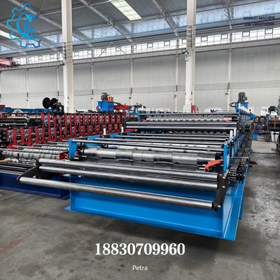 A imagem mostra o detalhe lateral da estrutura robusta em a&ccedil;o 300H. A pintura industrial azul combinada com m&uacute;ltiplos conjuntos de rolos de conforma&ccedil;&atilde;o evidencia uma estrutura s&oacute;lida e bem constru&iacute;da, com o fundo de uma moderna f&aacute;brica de produ&ccedil;&atilde;o.