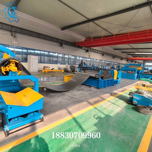 Side view of complete steel slitting line with metal coil being fed through the slitting process in a factory workshop